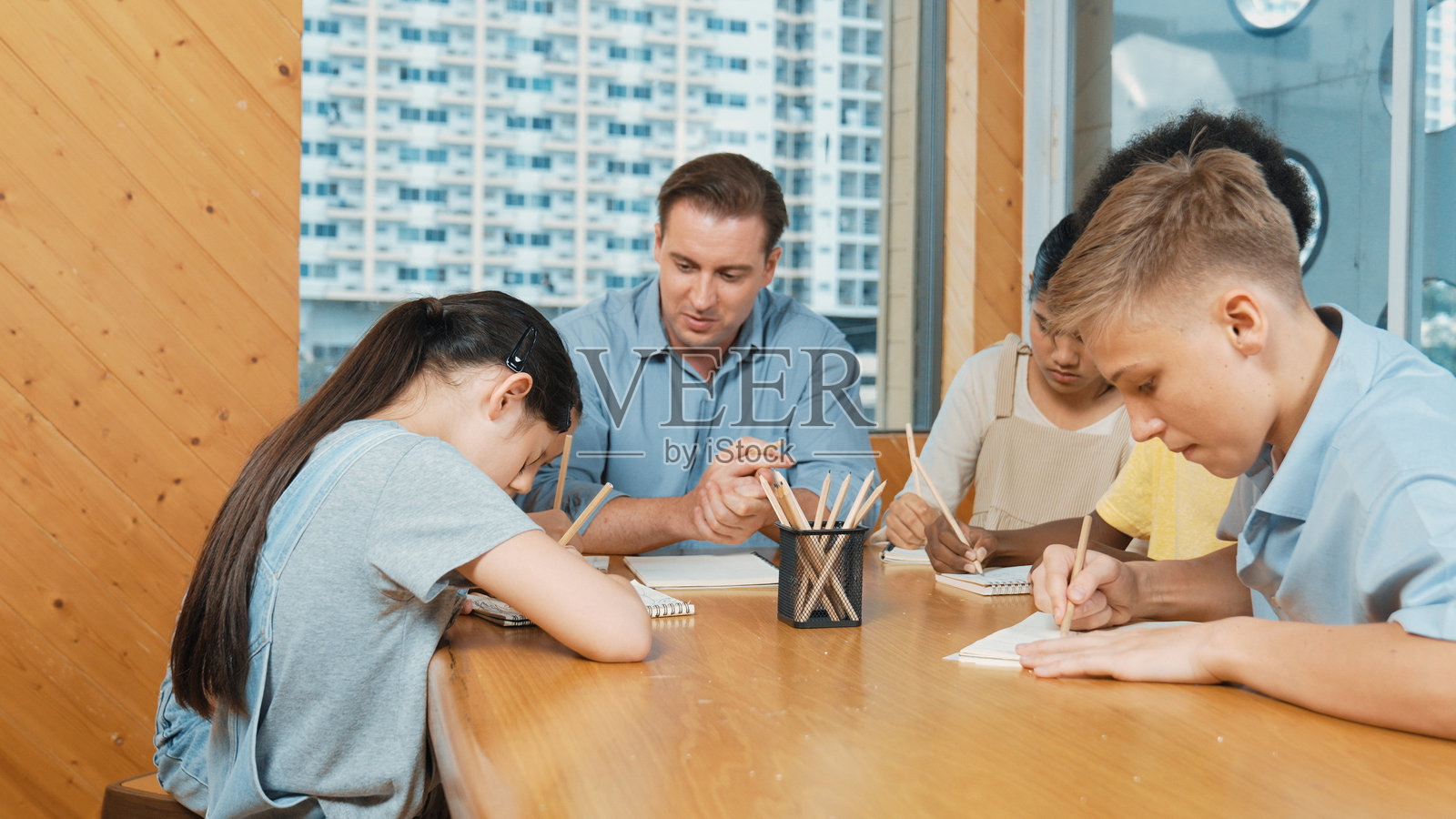 穿着休闲衬衫的男孩在询问老师，而另一名学生正在写书。启蒙教育。照片摄影图片