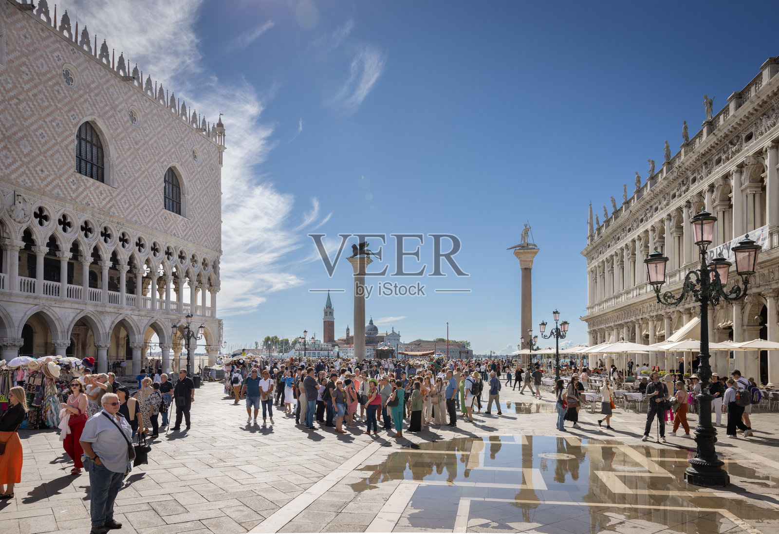 游客在圣马可广场，背景是总督宫和圣托达罗柱。照片摄影图片