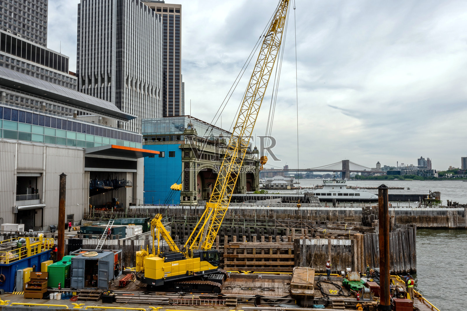 城市摩天大楼附近的海滨起重机工地施工活动,阴云密布的天气照片摄影图片