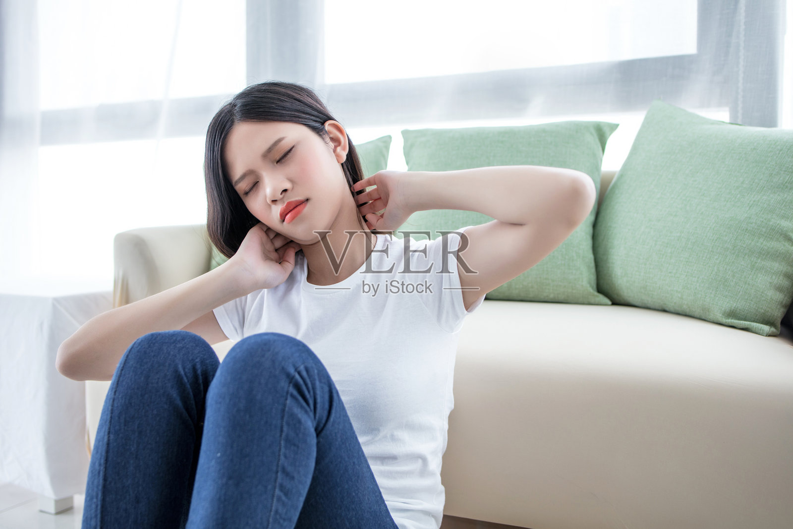 年轻女性坐在家里的地板上，手里拿着书，面向镜头。照片摄影图片