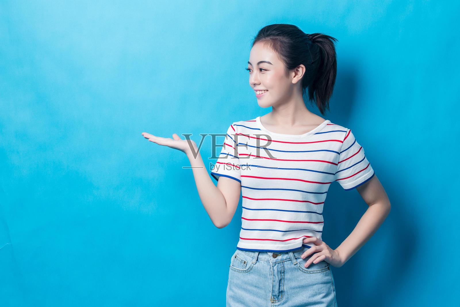 年轻的亚洲女性穿着休闲服装在蓝色背景前摆姿势照片摄影图片