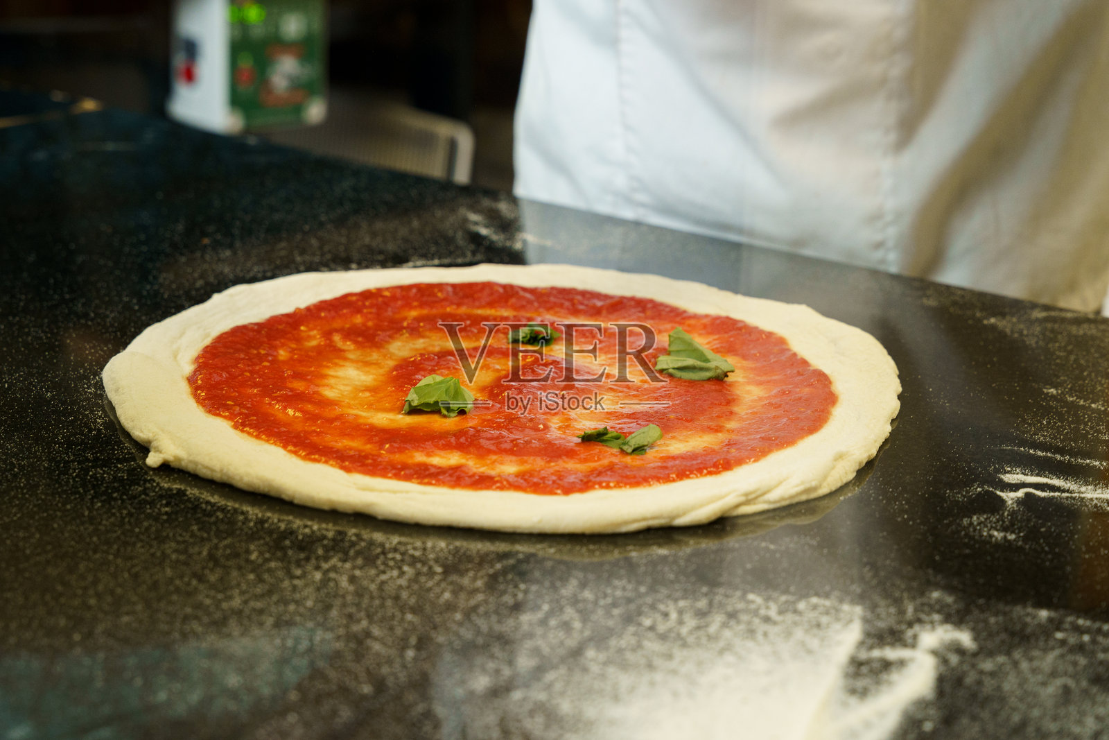 一位厨师正在准备番茄酱披萨照片摄影图片