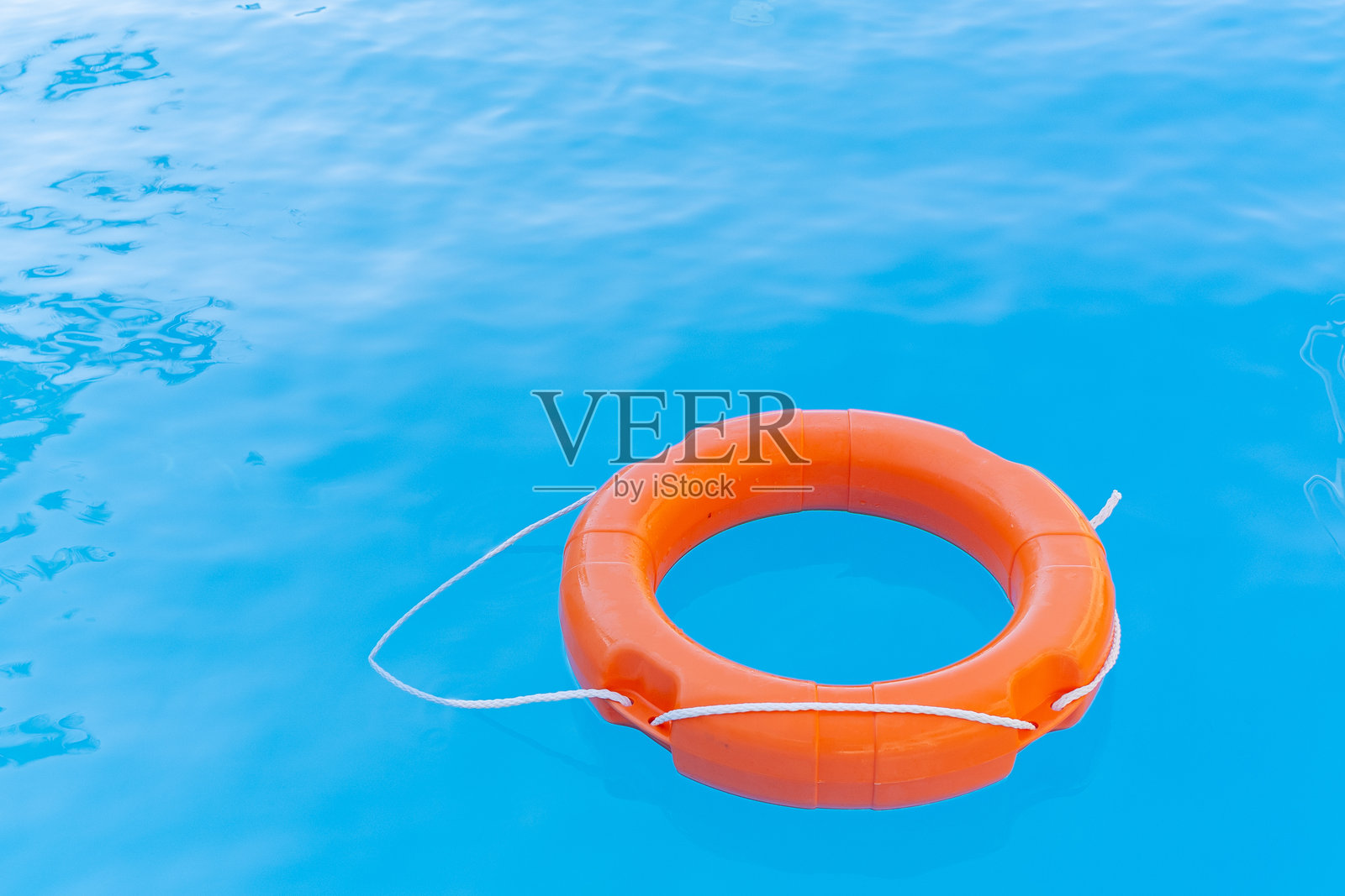 明亮的橙色救生圈漂浮在水面上，救助水中的人们照片摄影图片
