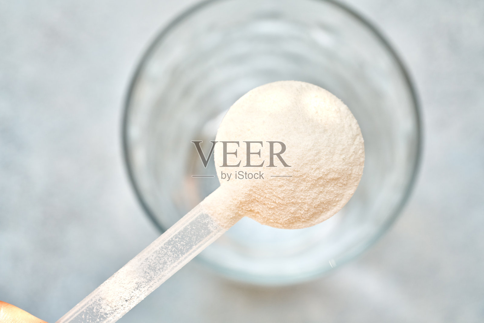 塑料勺中的胶原蛋白粉与一杯水照片摄影图片