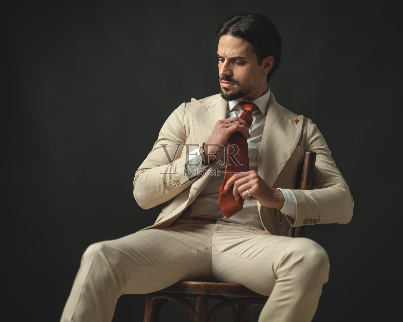 坐着的男性模特特写，正在整理他的红色领带照片摄影图片