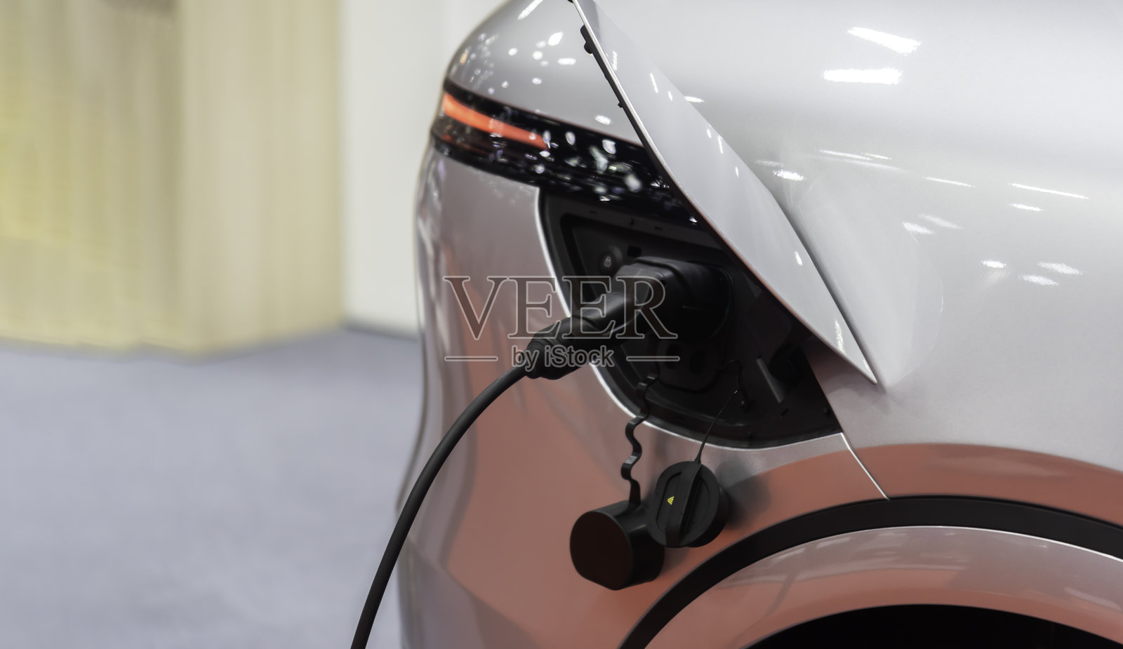 正在现代住宅建筑墙盒上充电的普通电动汽车照片摄影图片