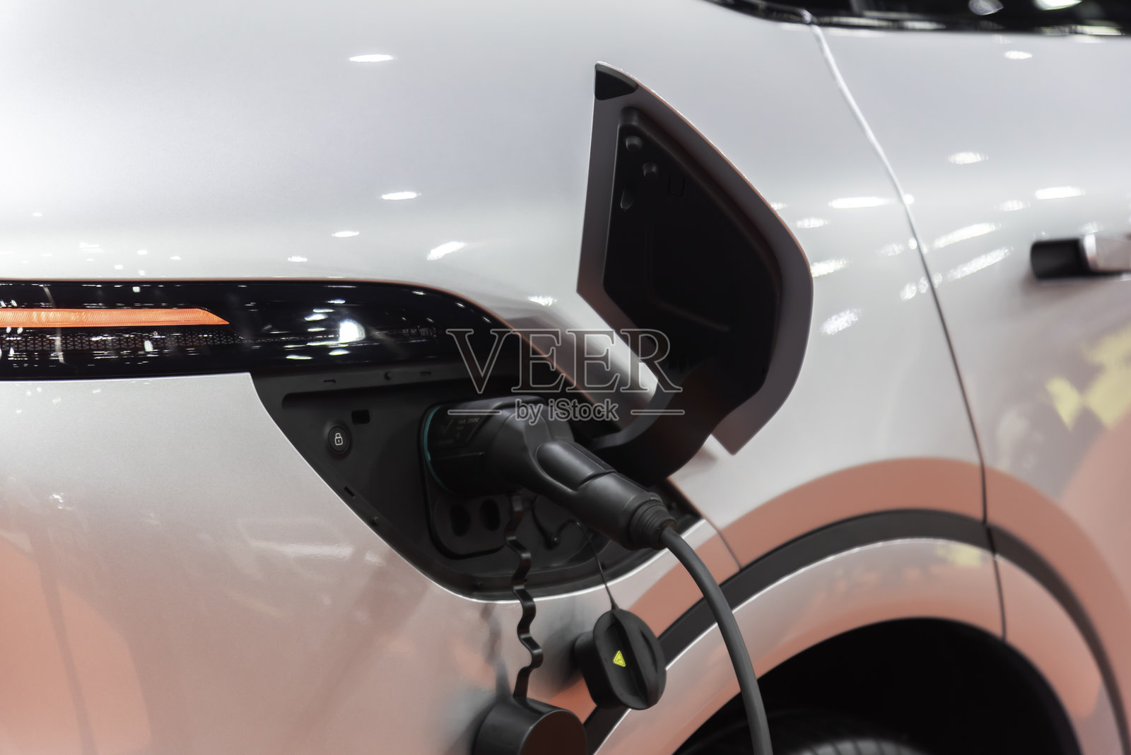 正在现代住宅建筑墙盒上充电的普通电动汽车照片摄影图片