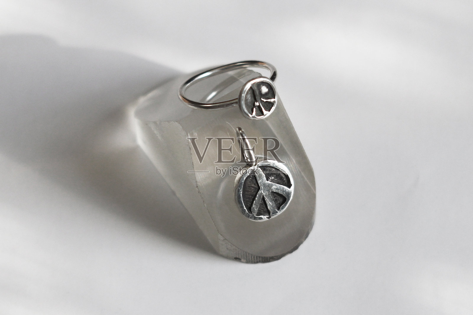 优雅的银色戒指和带和平符号的吊坠，背景为白色。手工制作的珍贵物品。珠宝配饰。照片摄影图片