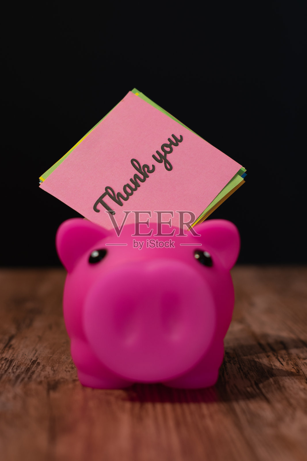 放在木质表面黑色背景的粉色感谢便条和储蓄罐照片摄影图片