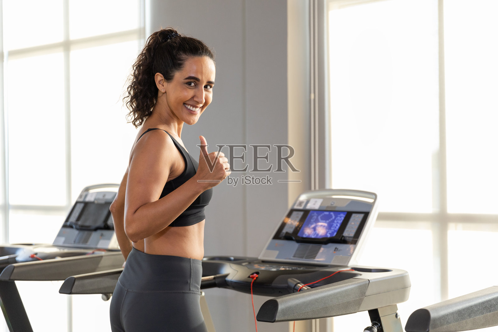 女性运动服锻炼在健身房跑步机上健身。运动员苗条，充满动力，燃烧卡路里。照片摄影图片