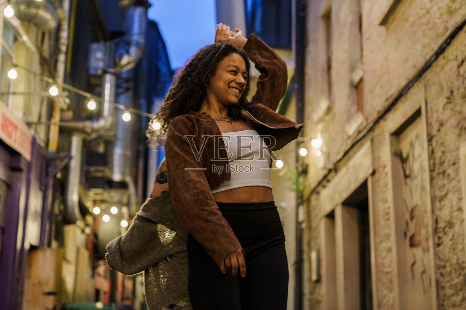 黑人妇女在灯光明亮的街道上与另一个女孩跳舞照片摄影图片