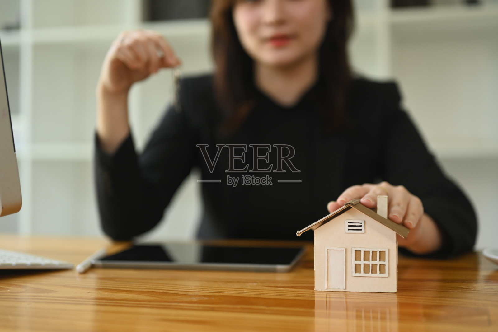 房地产经纪人手持钥匙和一个小房屋模型。房地产服务和投资概念照片摄影图片