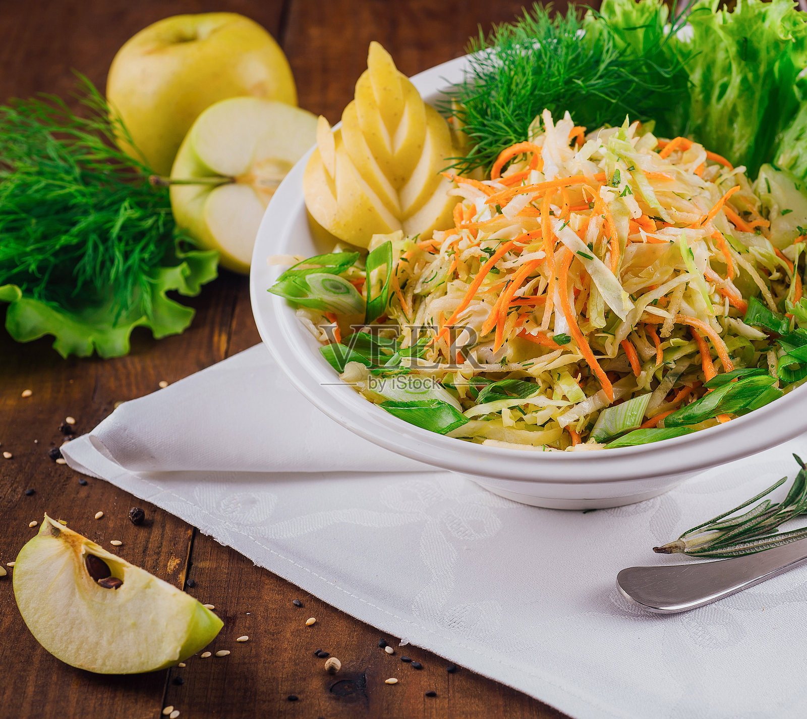 新鲜的卷心菜沙拉，配有苹果片和香草，摆放在木桌上照片摄影图片