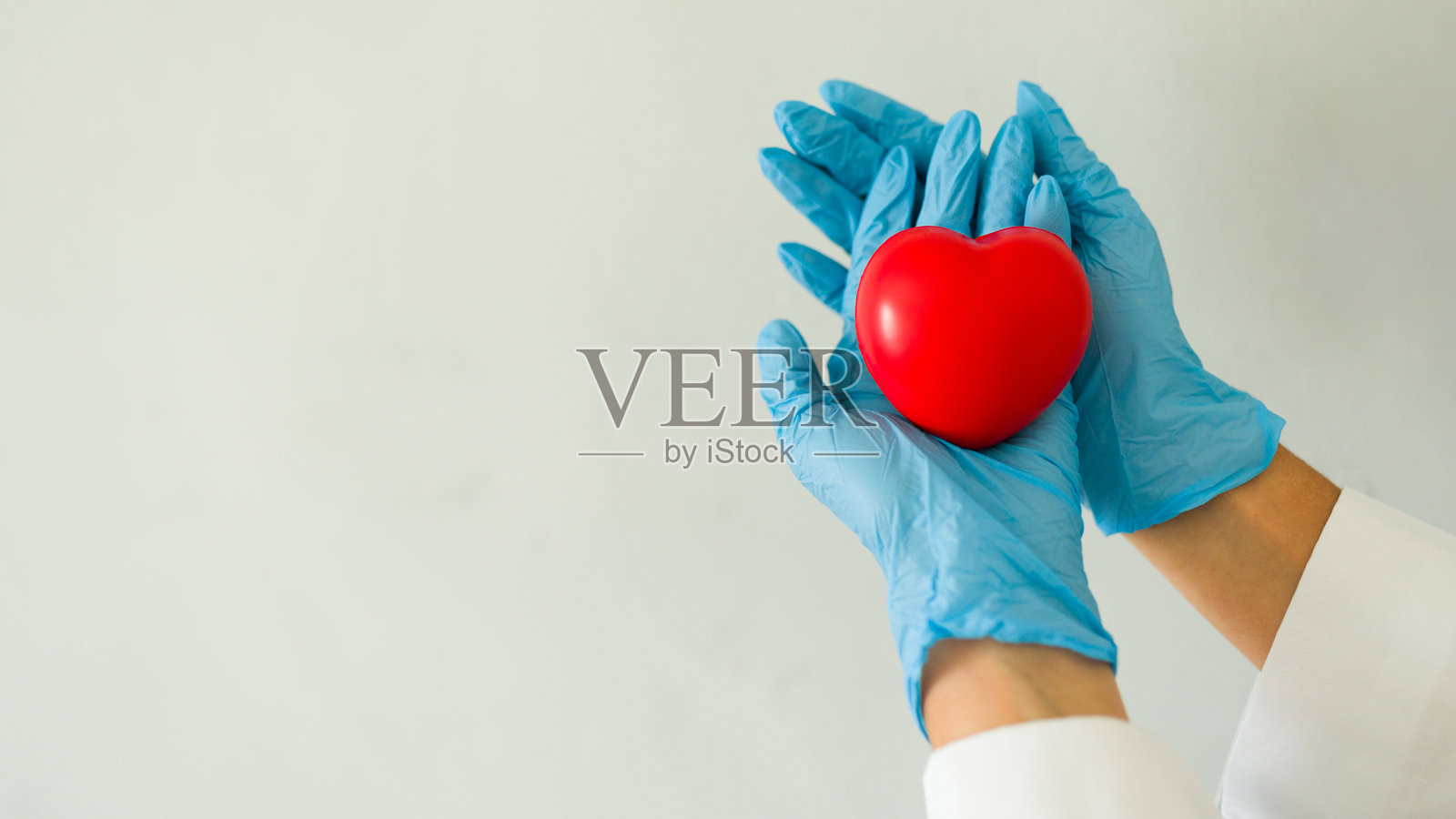 医生手持红色心脏，象征医疗和心脏病学照片摄影图片