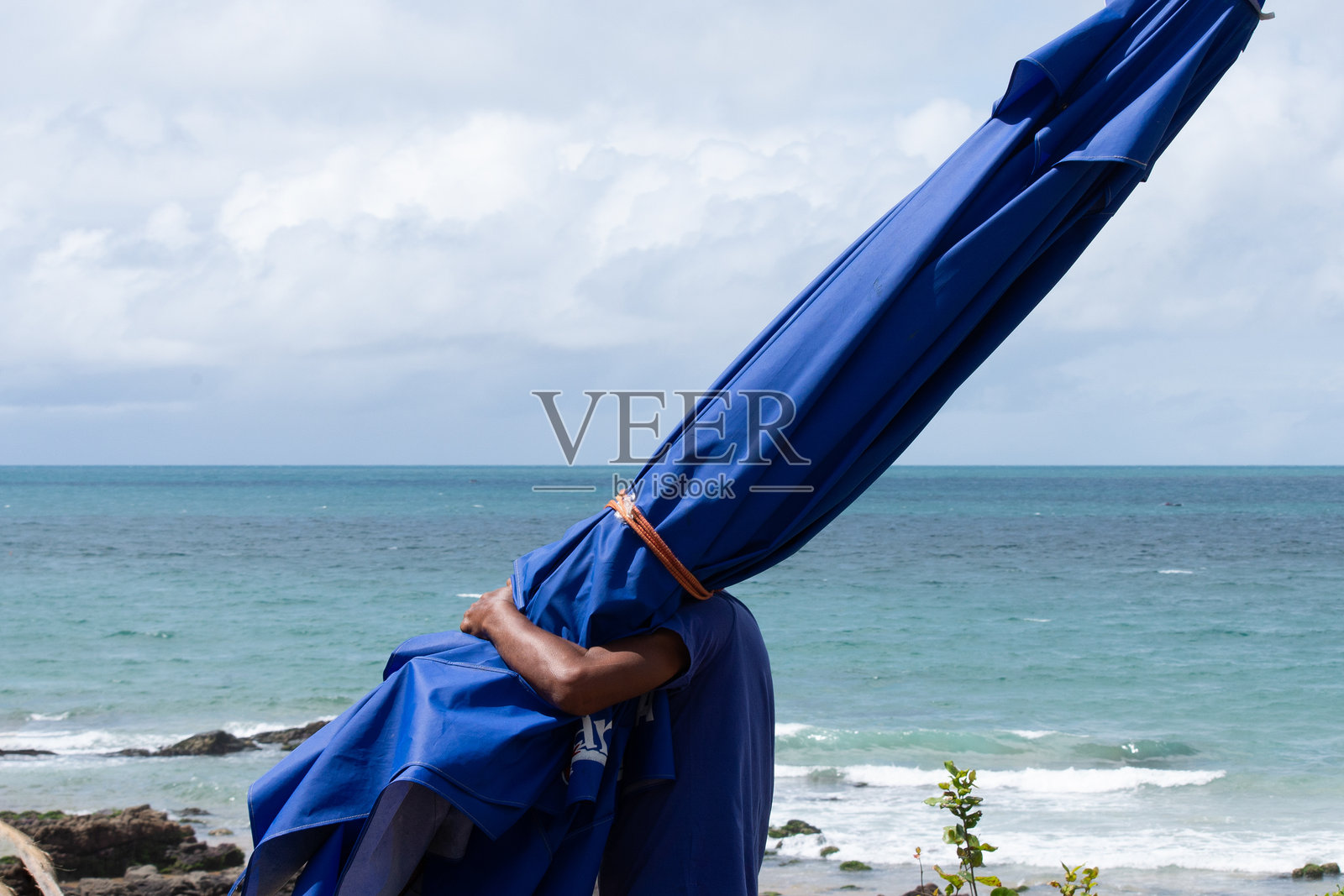 巴伊亚萨尔瓦多巴拉海滩强光下的海滩工人与蓝色遮阳伞照片摄影图片