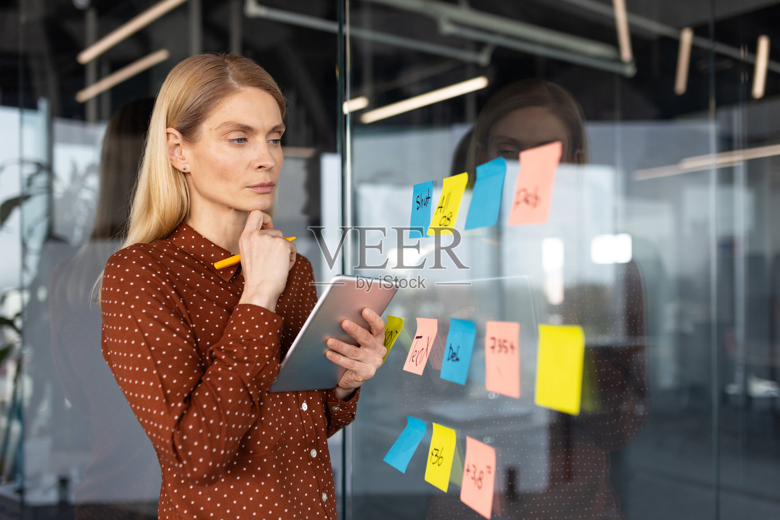 女商人用便利贴在玻璃墙上做计划照片摄影图片