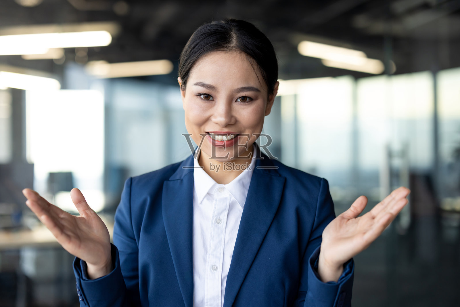 自信的亚洲女商人在现代办公环境中进行视频通话，面带微笑照片摄影图片