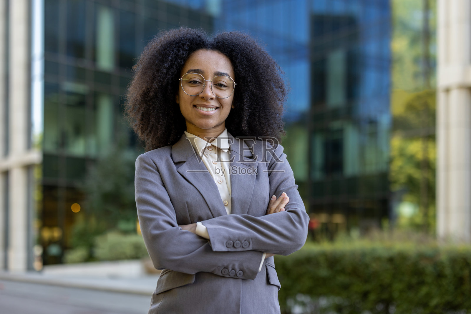 自信的年轻女商人在现代办公楼前交叉双臂站立照片摄影图片
