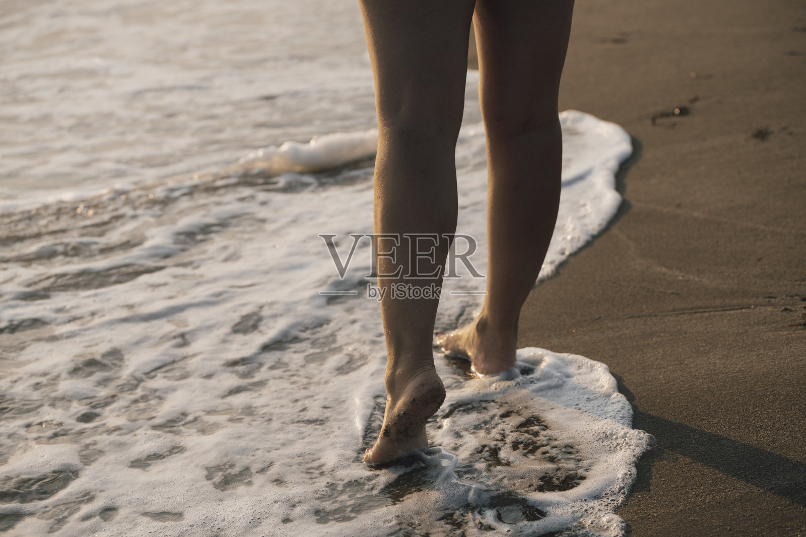 女性的腿在海滩上走过海水和沙子照片摄影图片