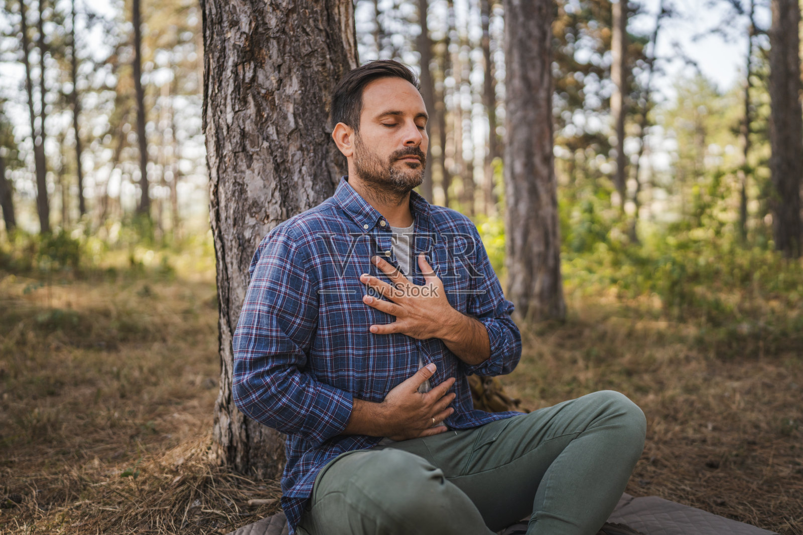 在树前练习冥想和呼吸的成年露营者照片摄影图片