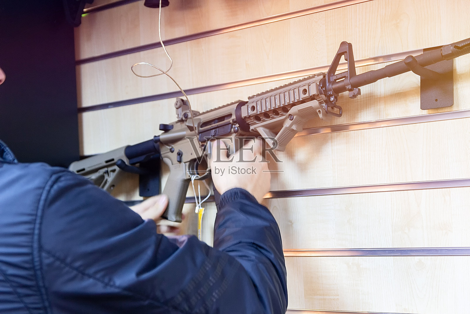 男子在枪店里手持自动步枪照片摄影图片