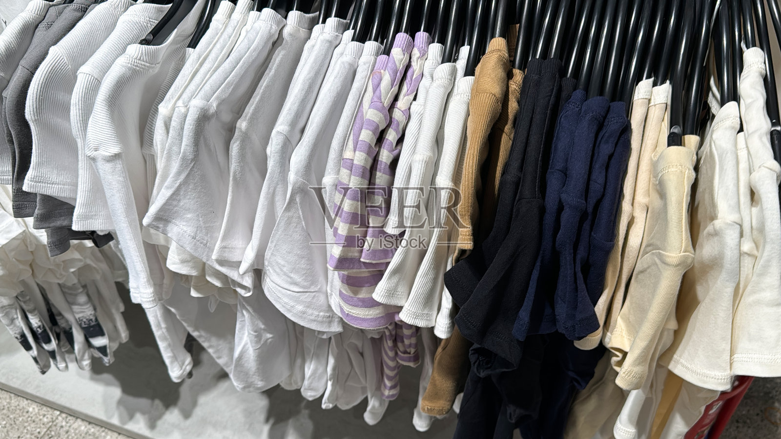 混合款式的T恤在时尚衣架上展示，色彩和风格丰富多样。照片摄影图片