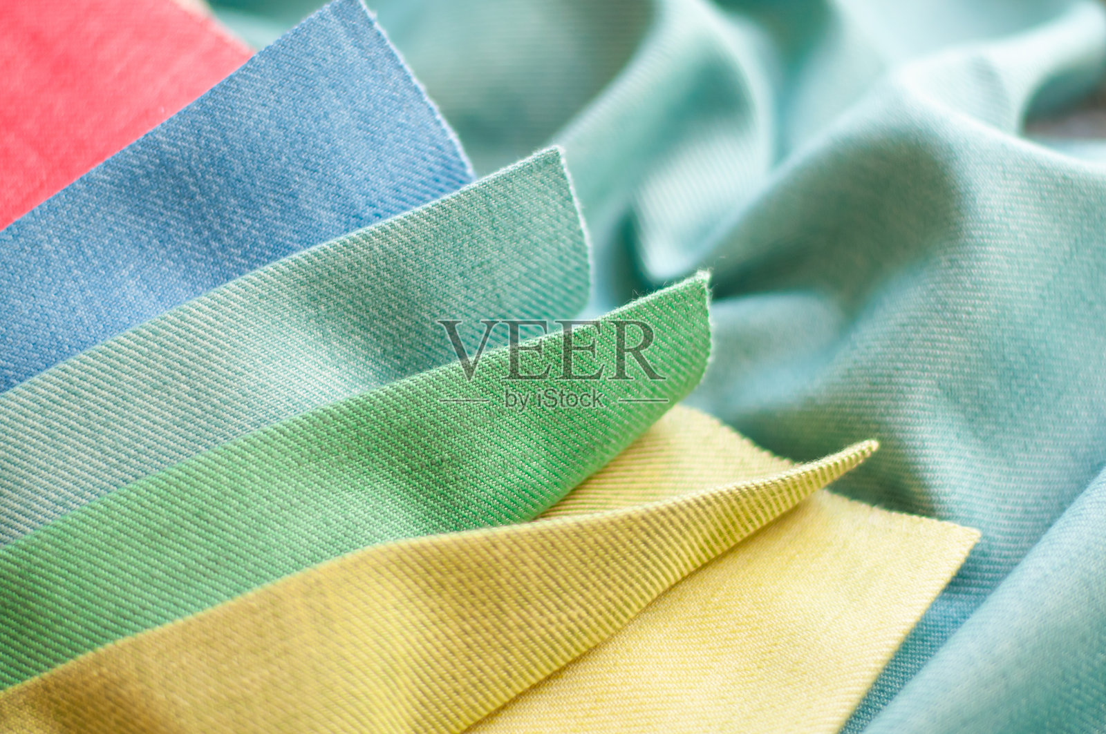 黄色、绿色和蓝色的布料样本放在绿色背景上。窗帘布料样本。照片摄影图片