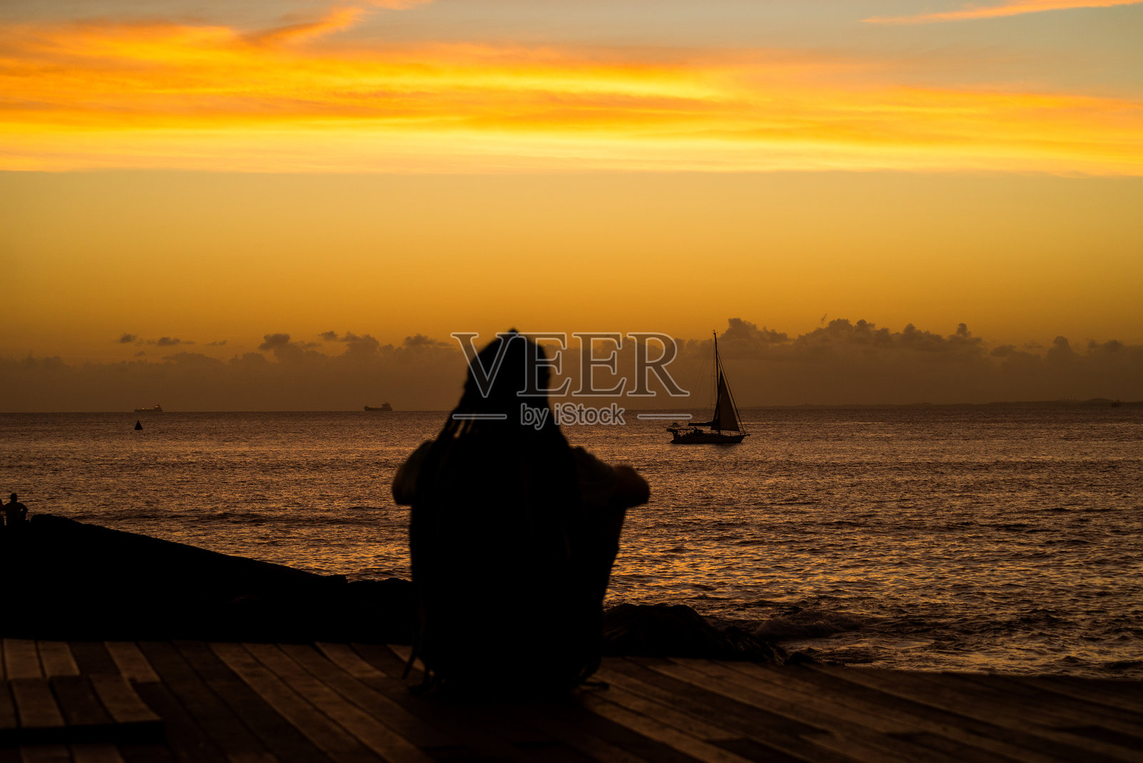 一个未被识别的人影在巴伊亚州萨尔瓦多的巴拉港享受日落和黄昏的美景。照片摄影图片