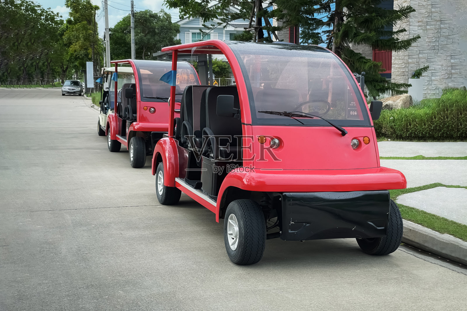 两辆漂亮的红色高尔夫球车停在俱乐部附近的路边，无人乘坐。它们专为搭载高尔夫球手在球场内行驶而设计照片摄影图片