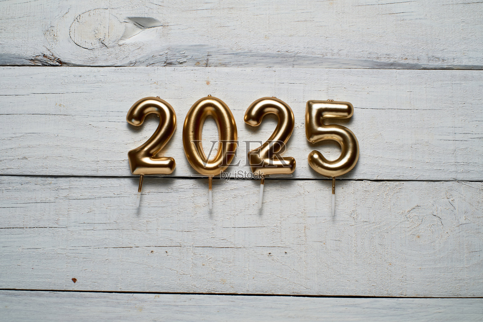 白色木质表面上的2025年形状的庆祝蜡烛。照片摄影图片