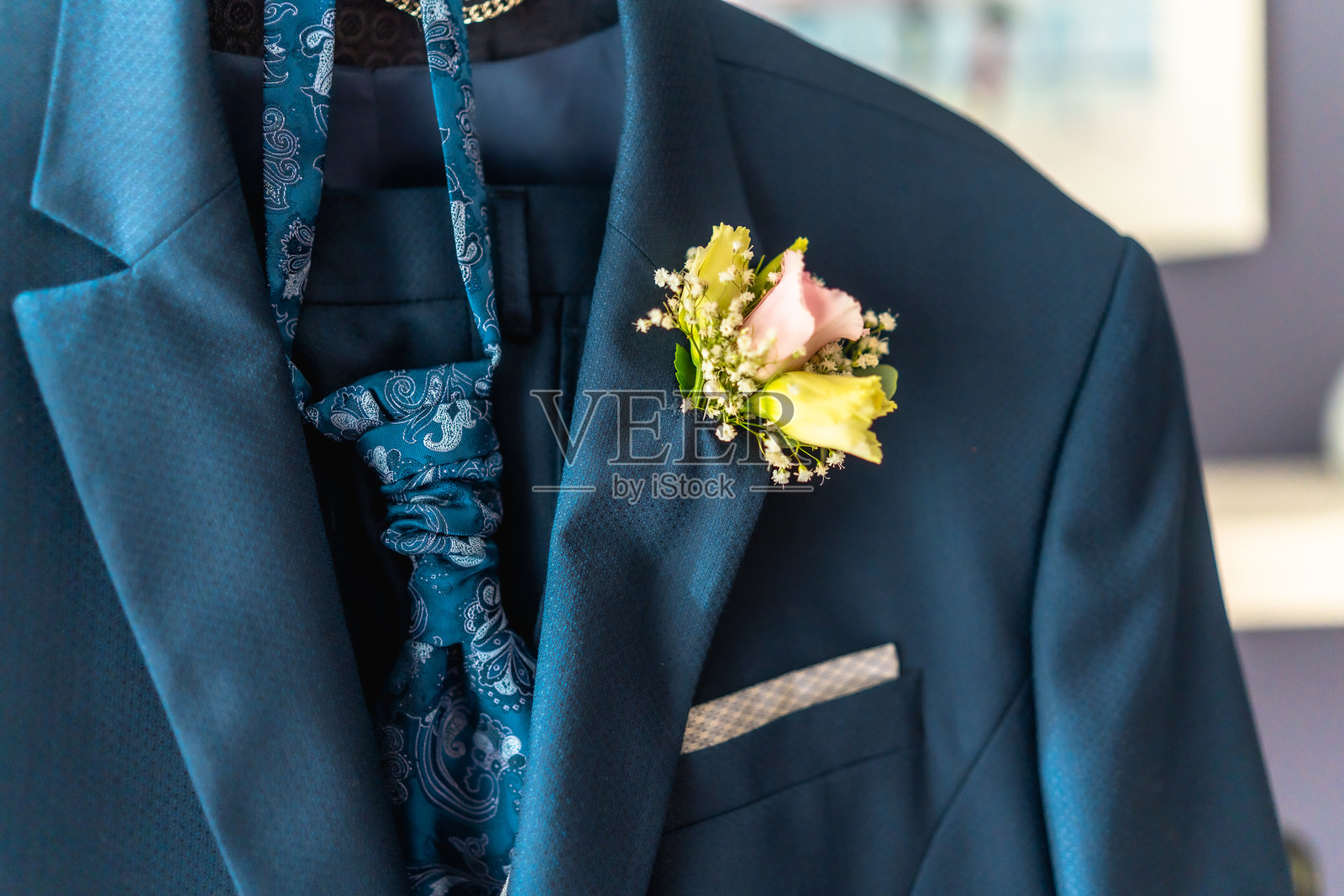 一名男子的蓝色西装外套上别着一朵粉色的胸花照片摄影图片