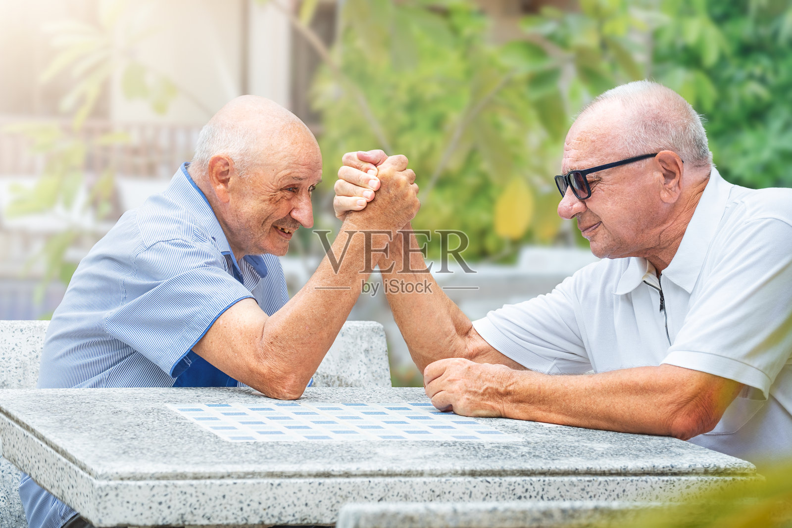 老年朋友们在桌子上进行臂力比赛照片摄影图片