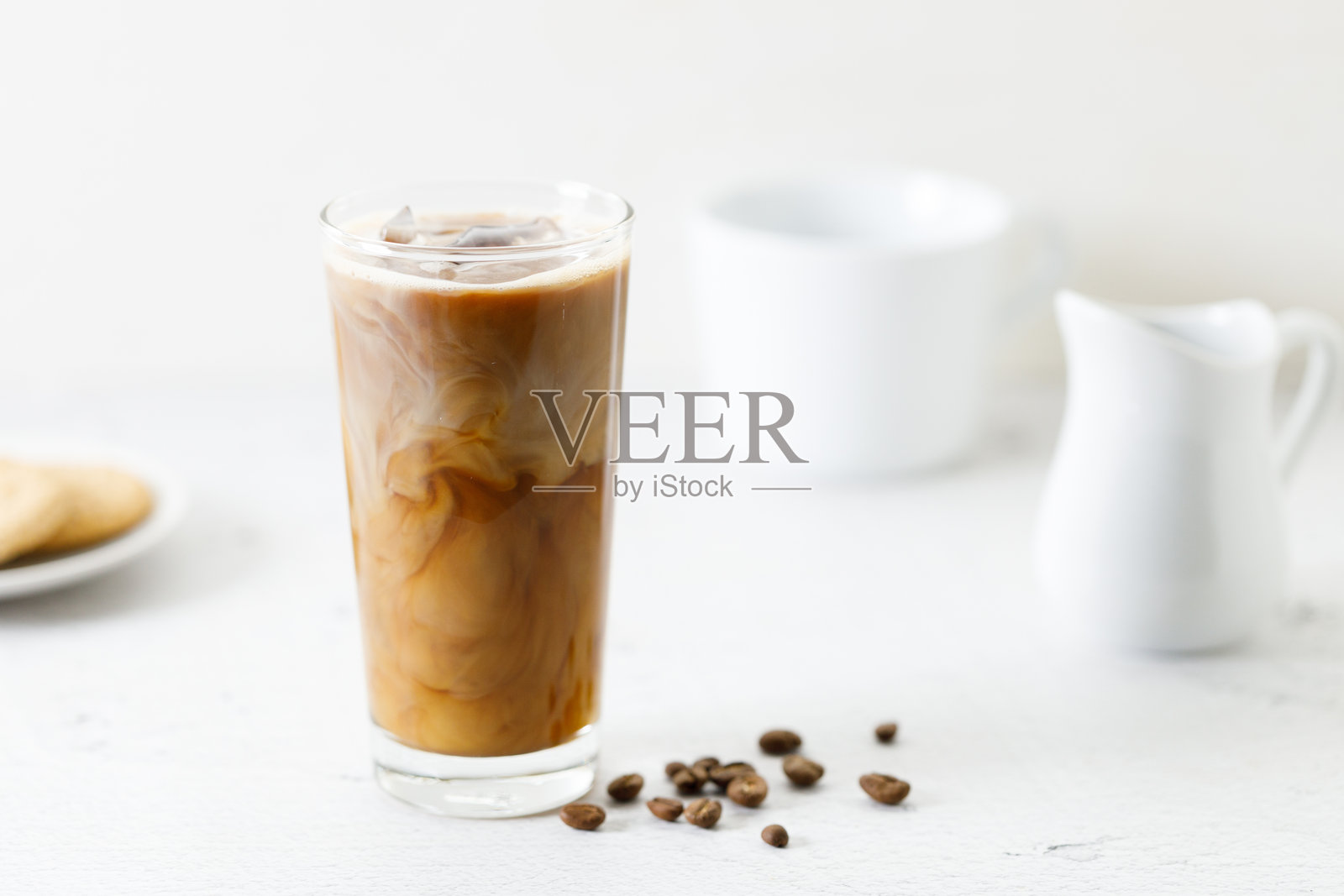 白色大理石桌子上的高杯冰咖啡，加入了牛奶。照片摄影图片