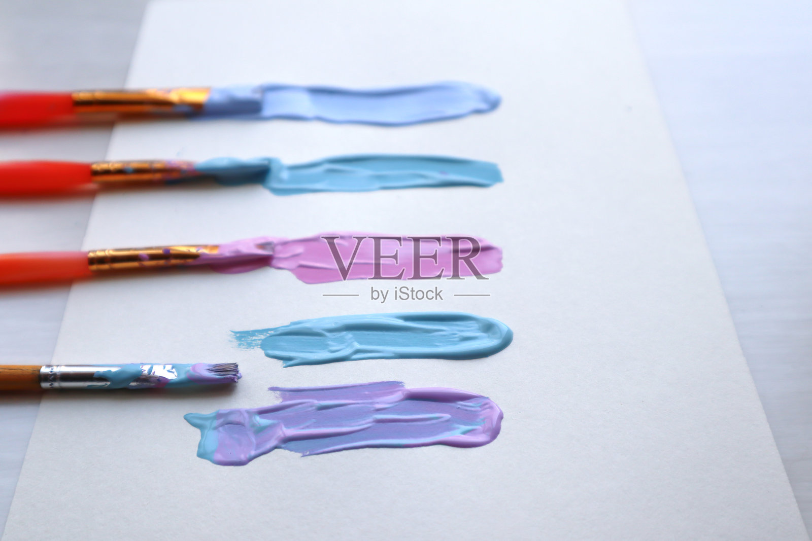 粉彩色调的丙烯颜料笔触在纸张上。丙烯颜料和画笔。照片摄影图片