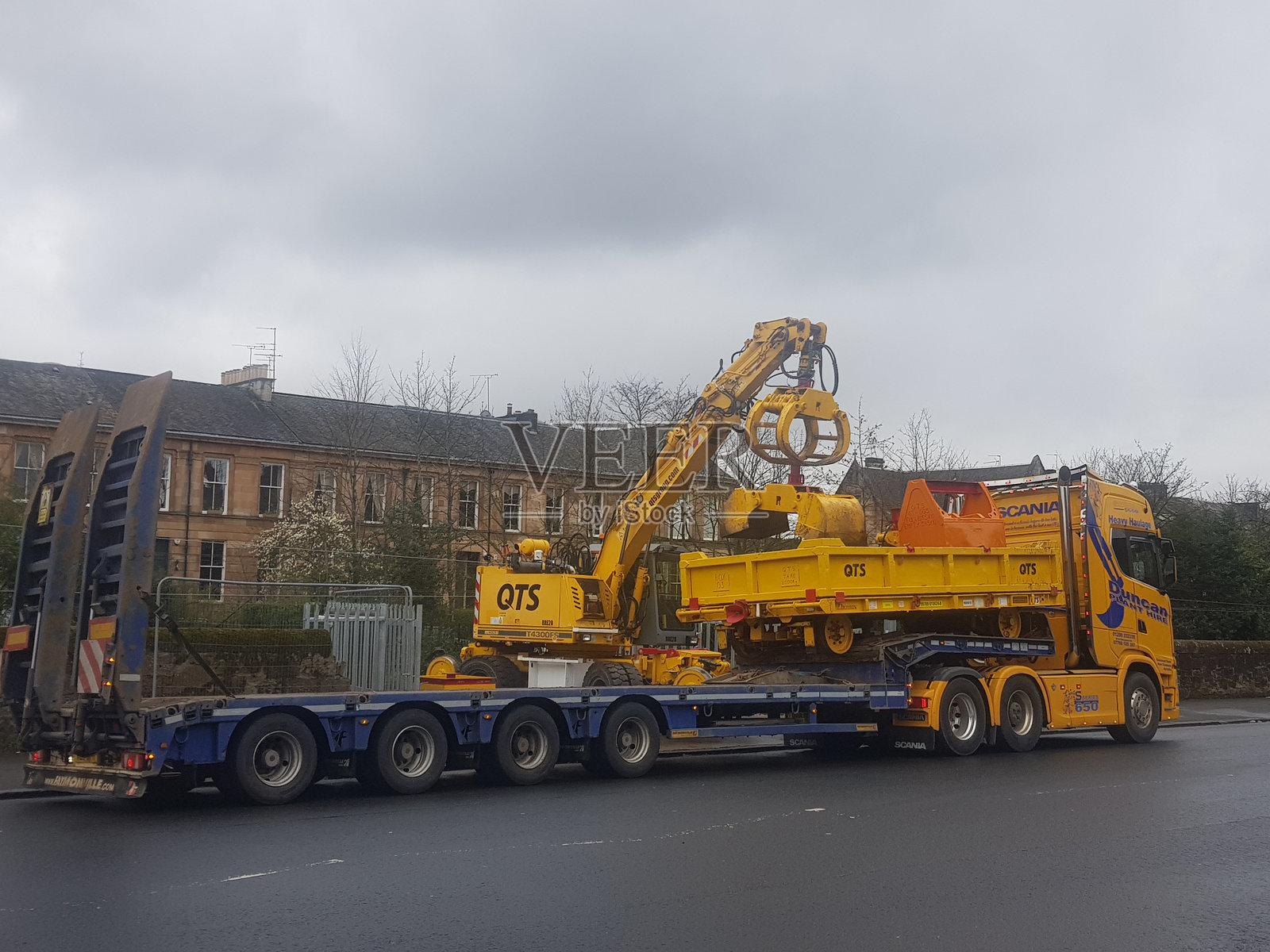 在苏格兰格拉斯哥,一辆低平板卡车上装载着公路铁路挖掘机的机械部分。照片摄影图片