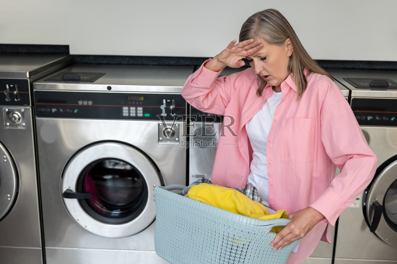 疲惫的成熟白人女性穿着粉色T恤，正在做家务。照片摄影图片