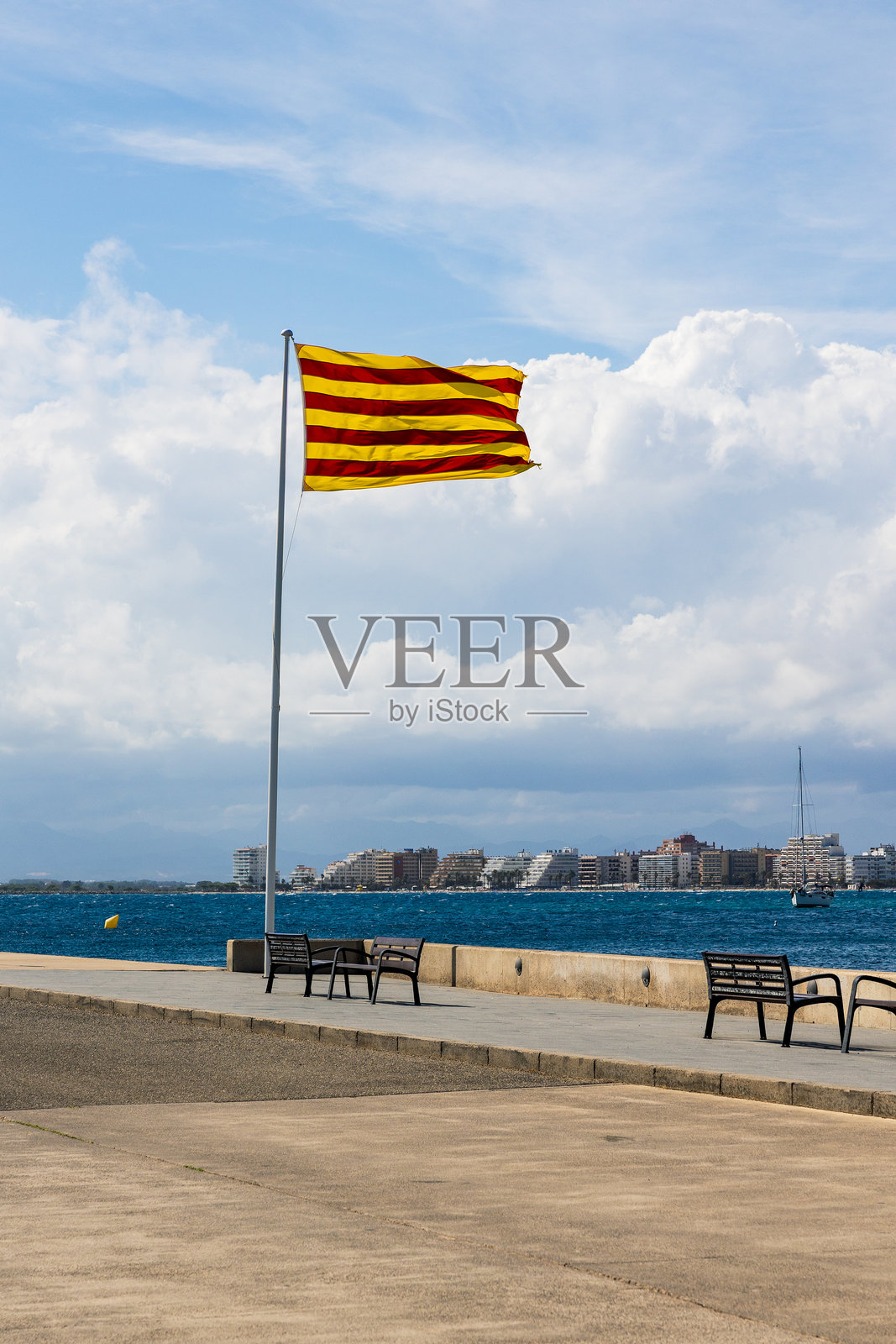 加泰罗尼亚旗帜在布拉瓦海岸的罗斯港口随风飘扬照片摄影图片