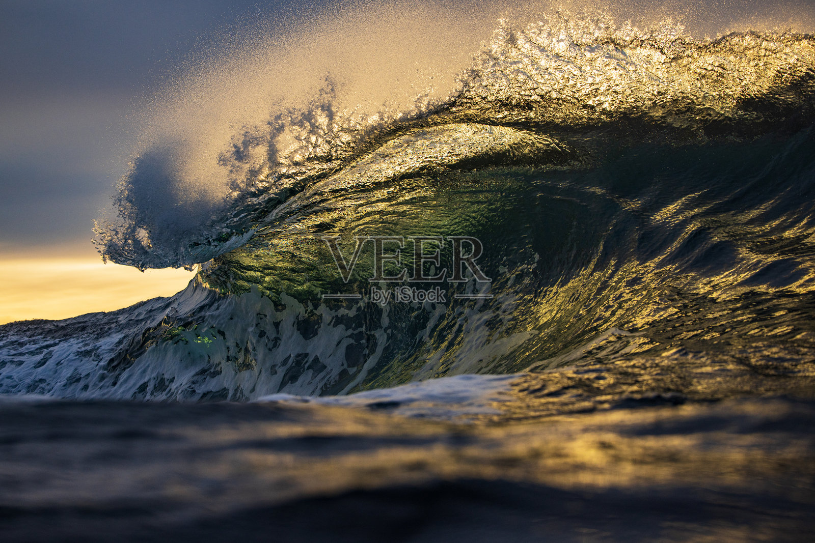 海浪在日出时分破碎，伴随着戏剧性的金色光芒特写。照片摄影图片