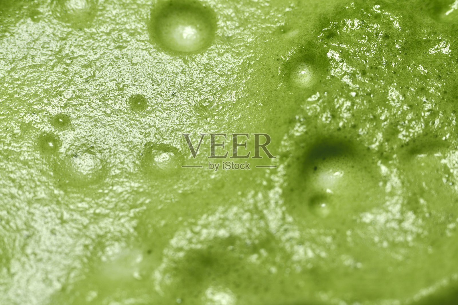 一张特写的绿茶图片，展现了光滑、泡沫丰富的质感。鲜艳的绿色和表面可见的气泡突显了绿茶的新鲜感，带来清凉和提神的感觉。照片摄影图片