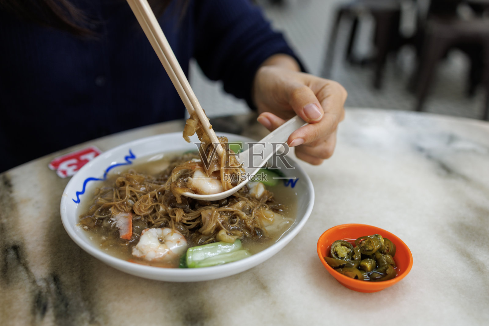 一位女性享用炒米粉配猪肉和虾，浸泡在浓厚美味的酱汁中，也被称为炒河粉。照片摄影图片