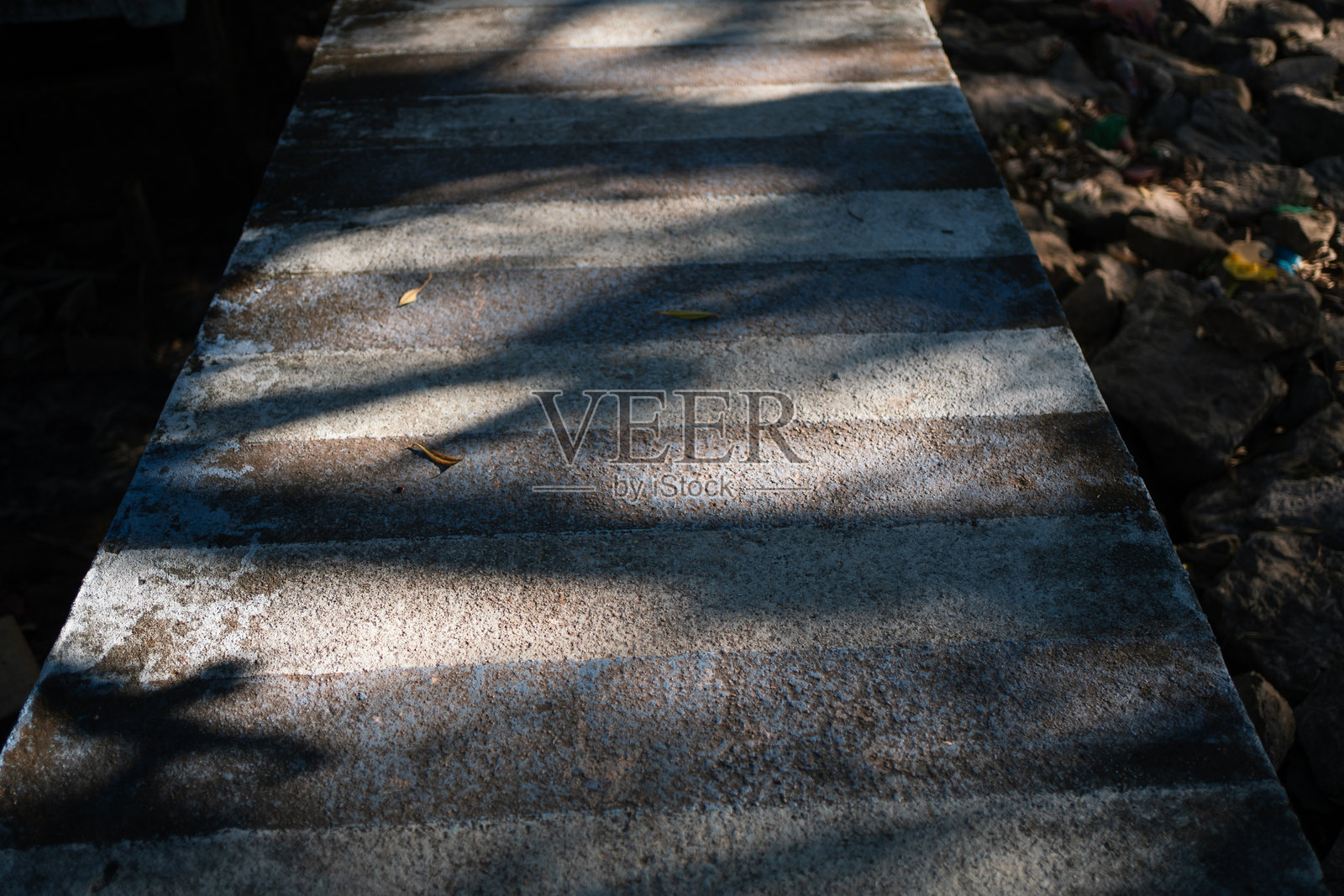 阳光和阴影照射下的旧混凝土人行道灰色石纹理。照片摄影图片