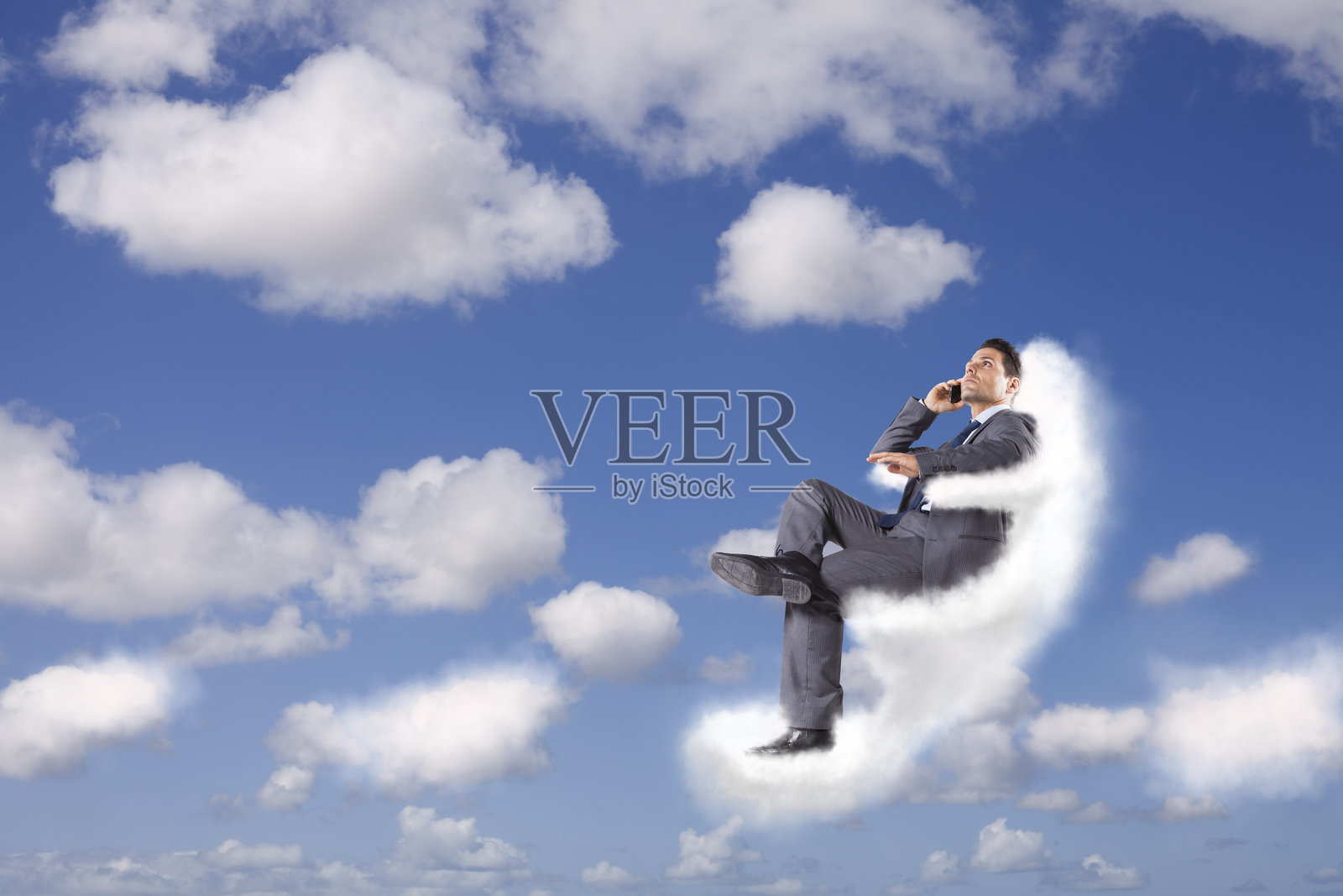 商人坐在云端，进行着超越传统界限的电话通话。照片摄影图片