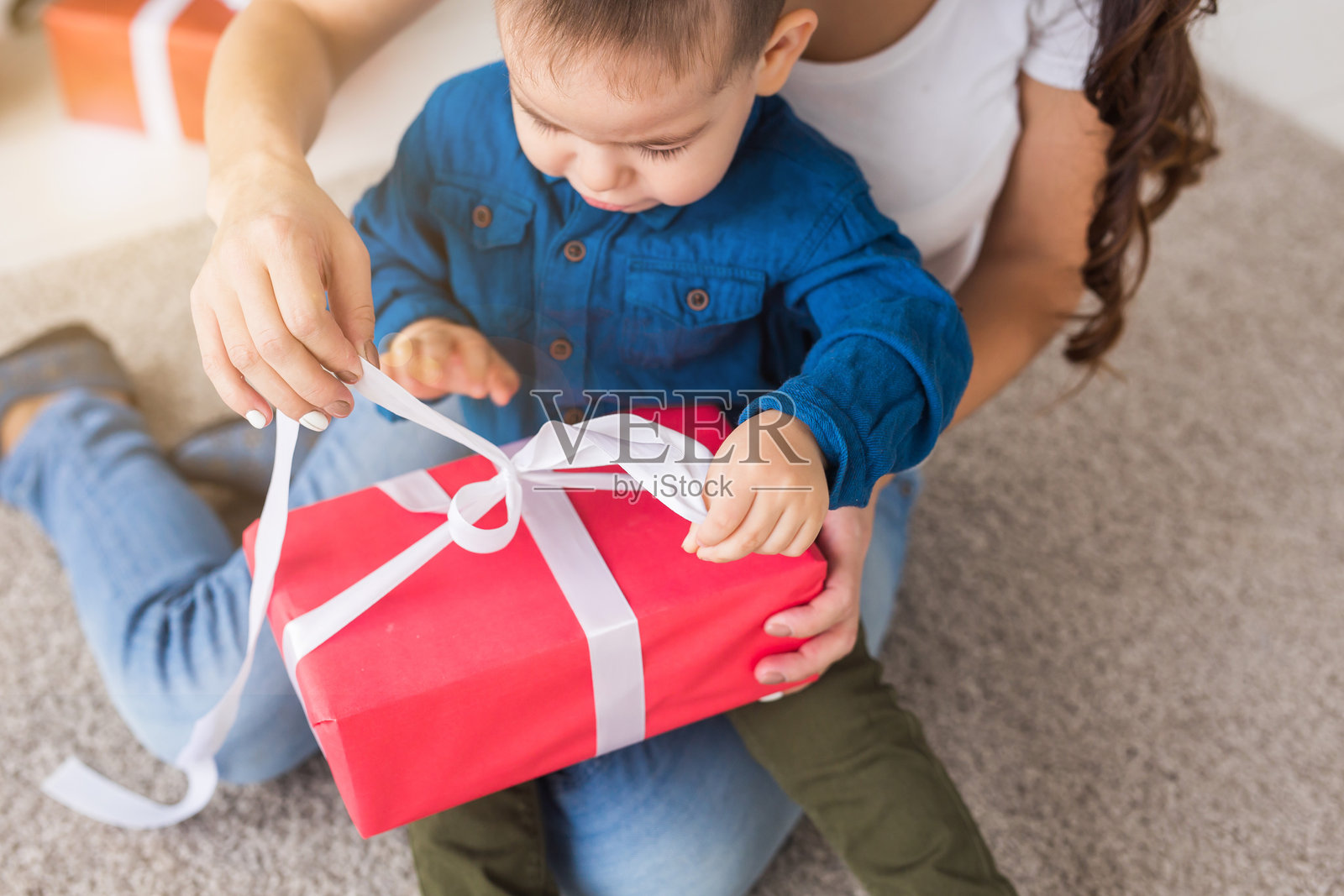 小男孩和妈妈一起拆礼物盒。礼物、儿童、生日和节日概念照片摄影图片