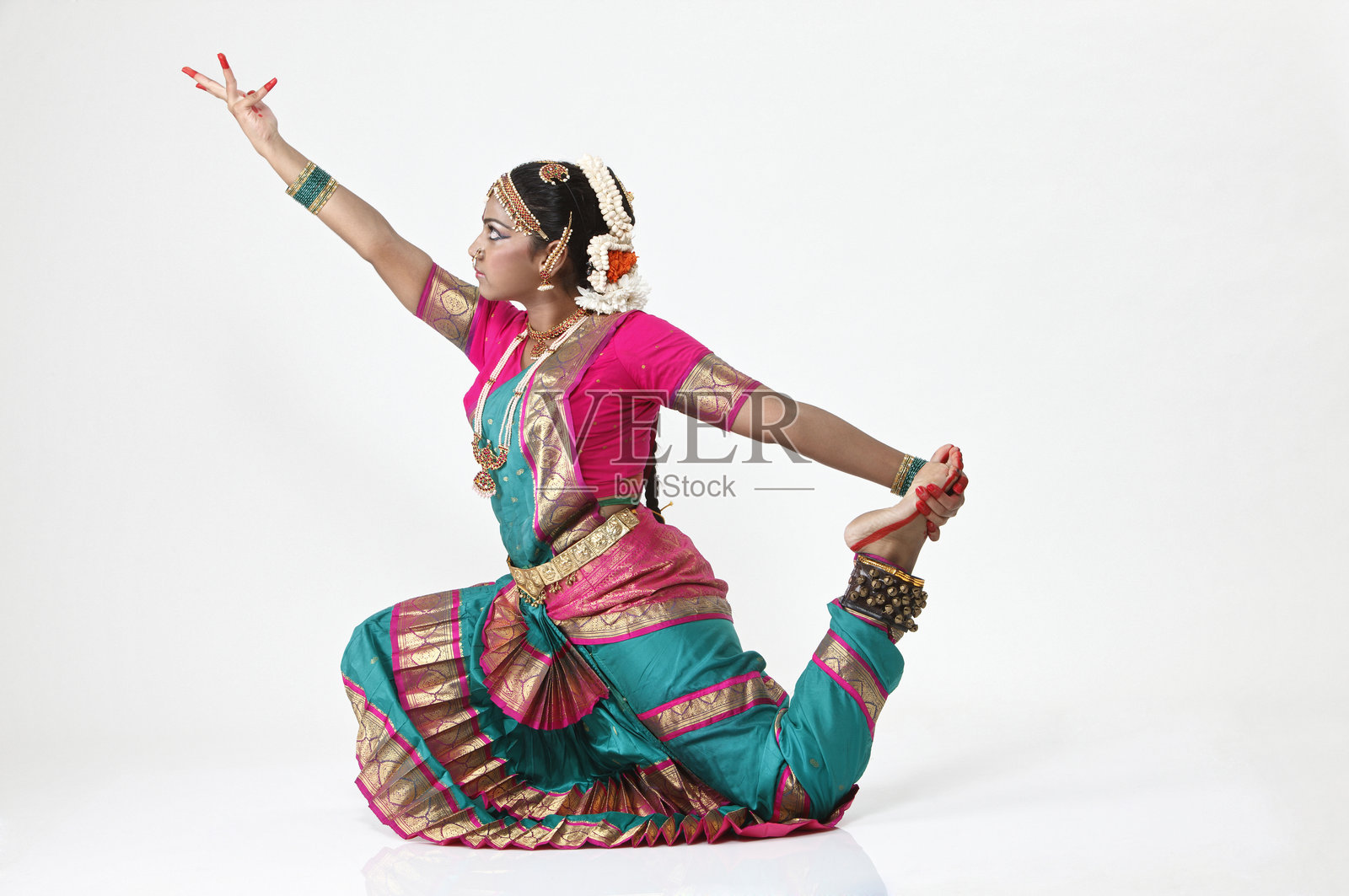 年轻女性身穿传统服饰和珠宝，在白色背景下跳舞照片摄影图片