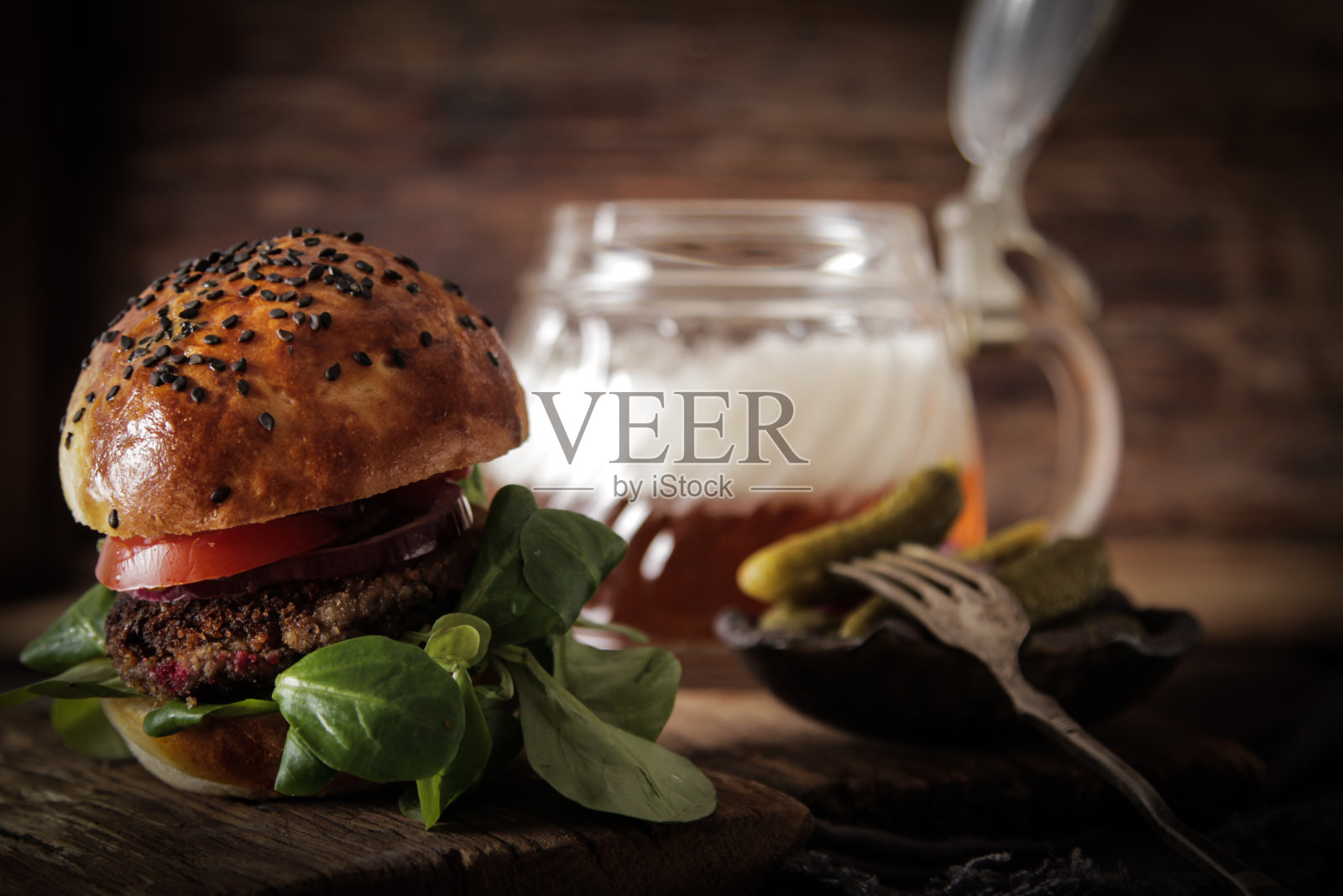 自制素食汉堡夹在撒有啤酒芝麻的面包中，美味可口。照片摄影图片