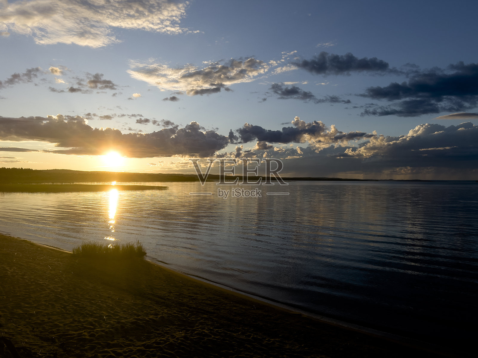 美丽的红色日落带有橙色的色调，湖岸边放松，旁边有一个水壶和茶，还有一个吊床和一个冲浪板供游泳和运动，健康的户外休闲活动，夏季天气。照片摄影图片