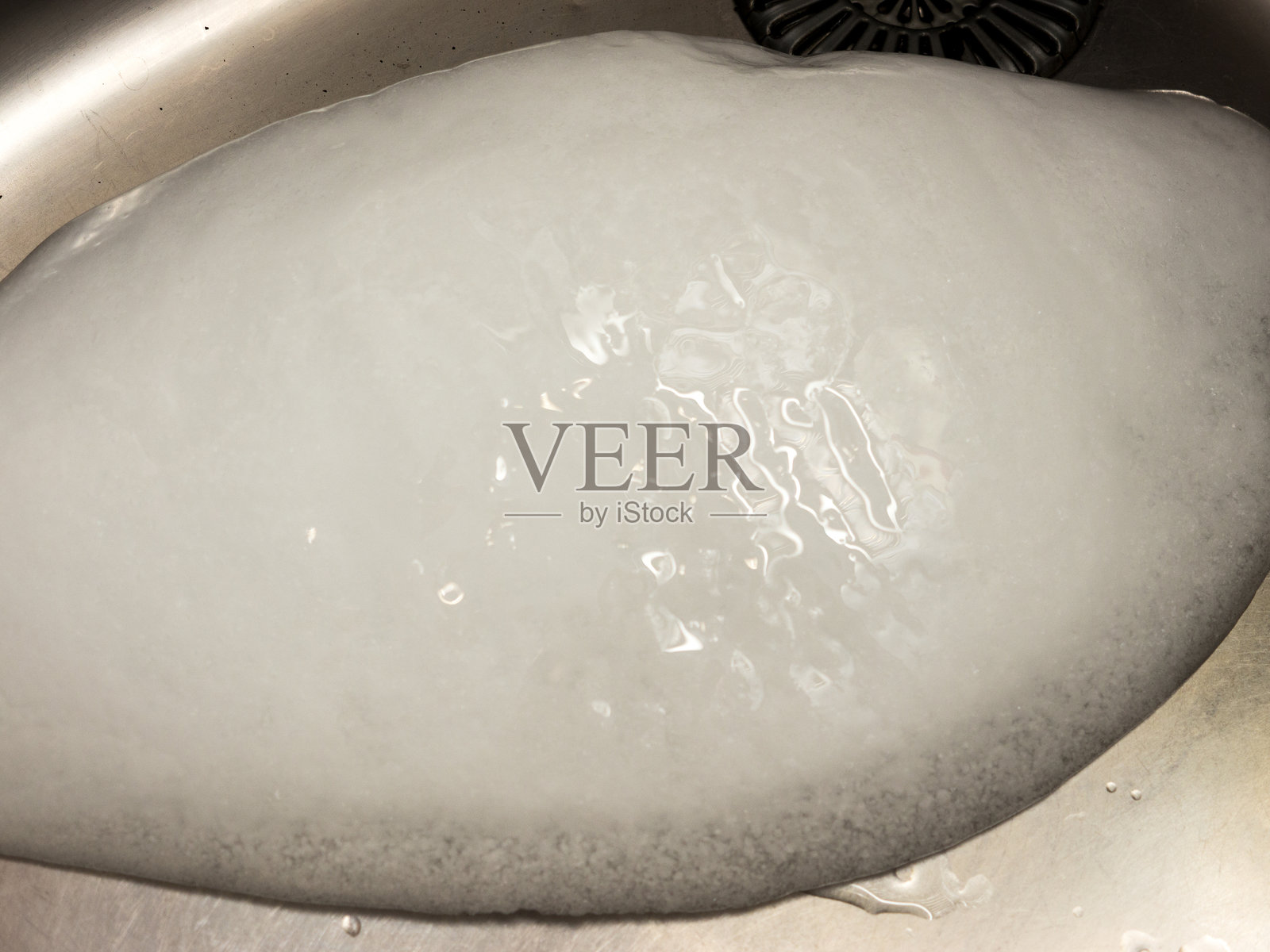 金属水槽中的一块冰。照片摄影图片