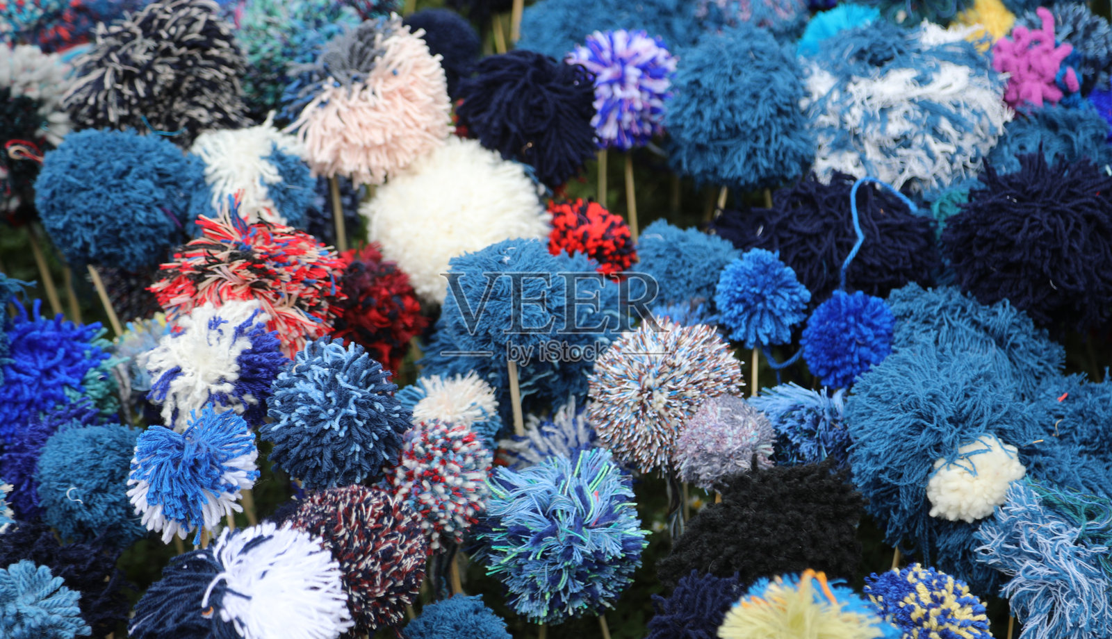 用毛线球制作的许多花朵，形成了一个令人惊叹的多彩背景。照片摄影图片