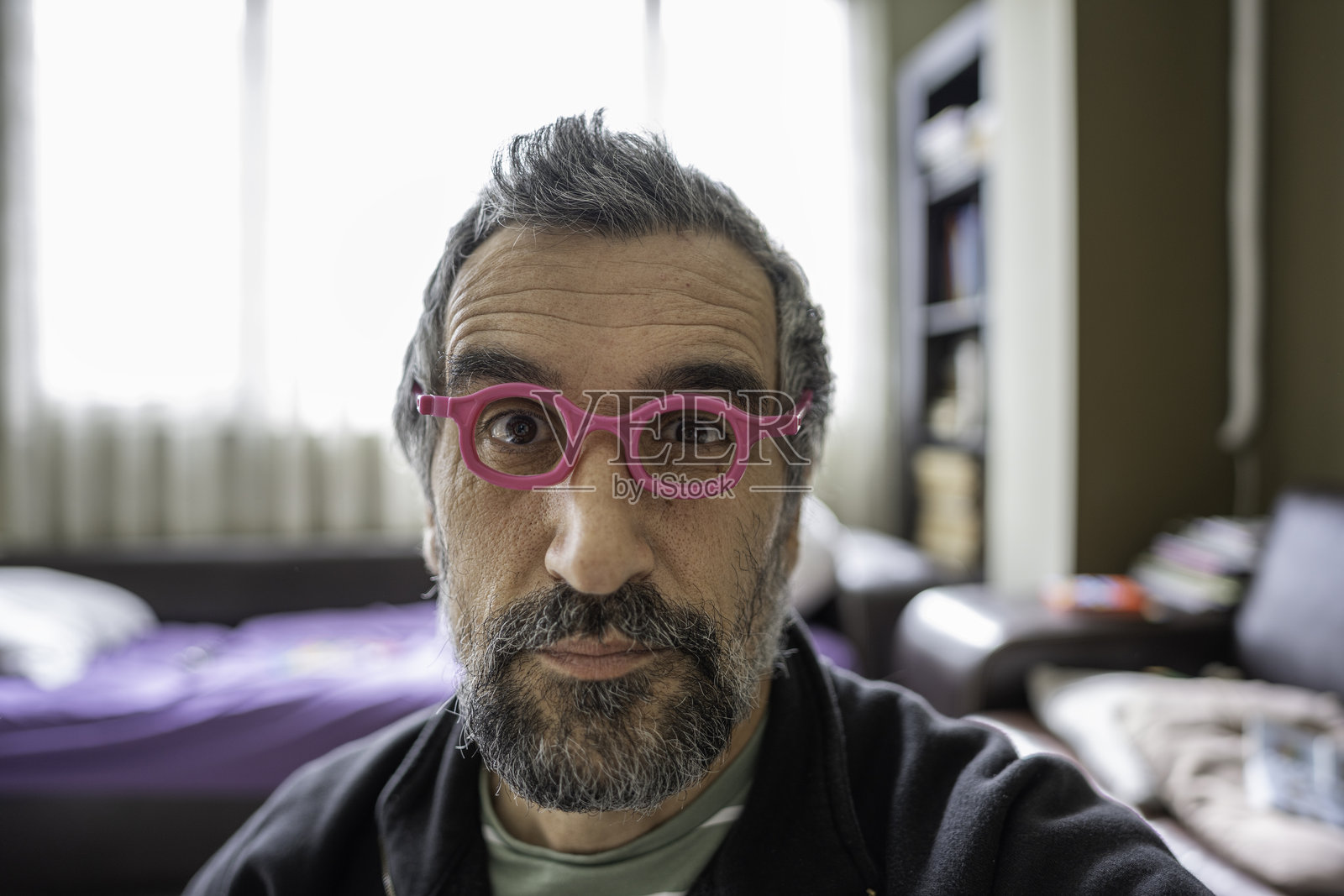 成熟男人戴着粉色儿童眼镜，面露搞笑表情照片摄影图片