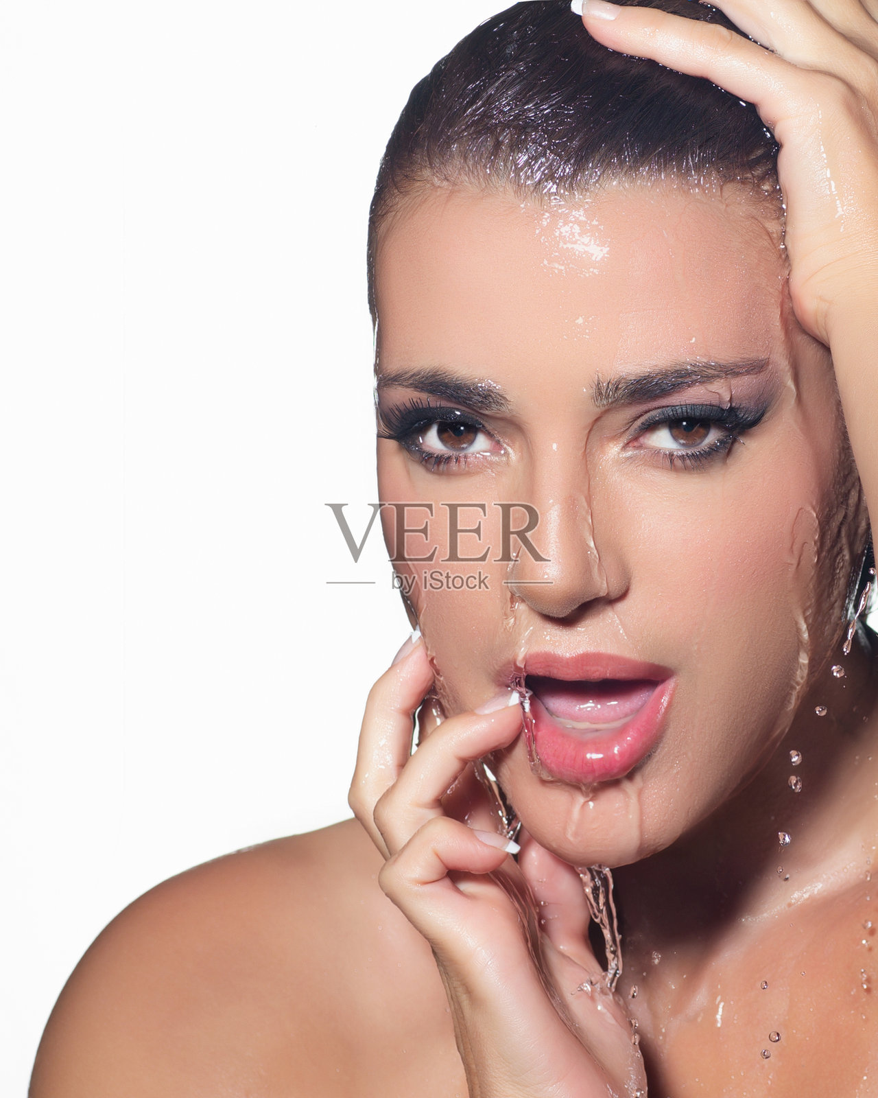 水花飞溅的美丽女性面部肖像，展现无瑕肌肤和防水妆容。保湿护肤概念照片摄影图片